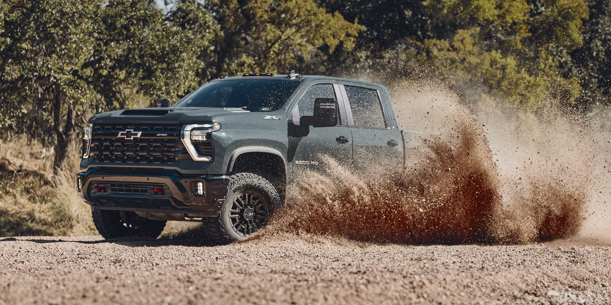Exterior Side View Of A 2026 Chevy Silverado Hd Driving Off Road Through A Desert